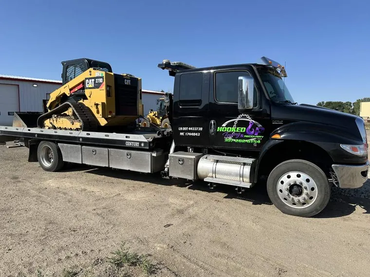 CAT skid steer loaded on Hooked Up Towing flatbed for equipment transport in Wyoming